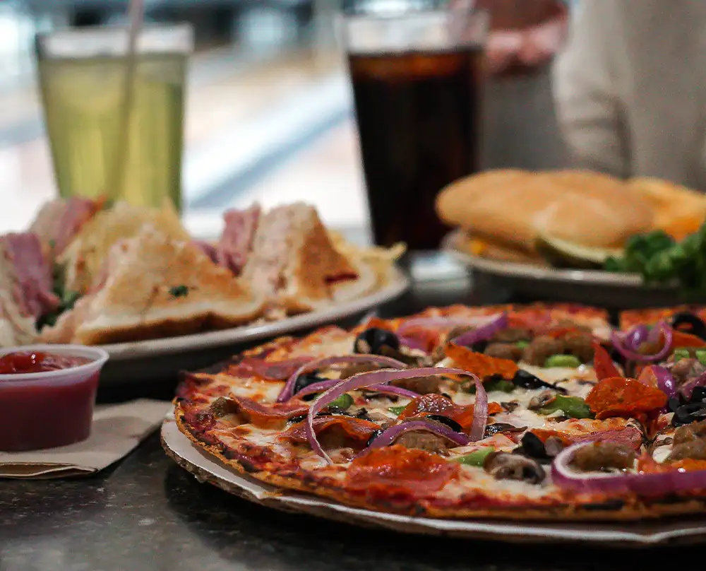 Pizza topped with pepperoni and red onion beside sandwiches and sodas from the snack bar at Bel-Air Bowl in Belleville, IL