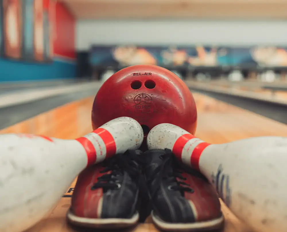 Red Bel-Air house bowling ball and rental shoes between two fallen pins on a lane at Bel-Air Bowl in Belleville, IL