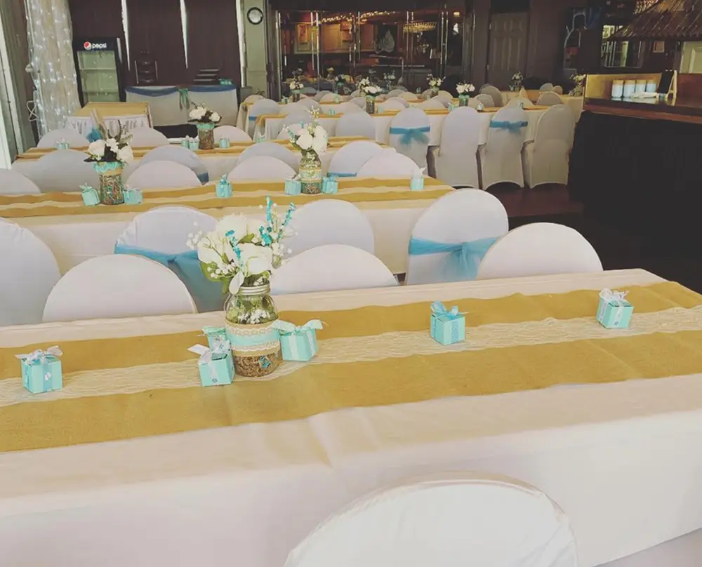 Banquet hall set with white chair covers, teal ribbons, and floral centerpieces for a Bel-Air Banquets event at Bel-Air Bowl in Belleville, IL