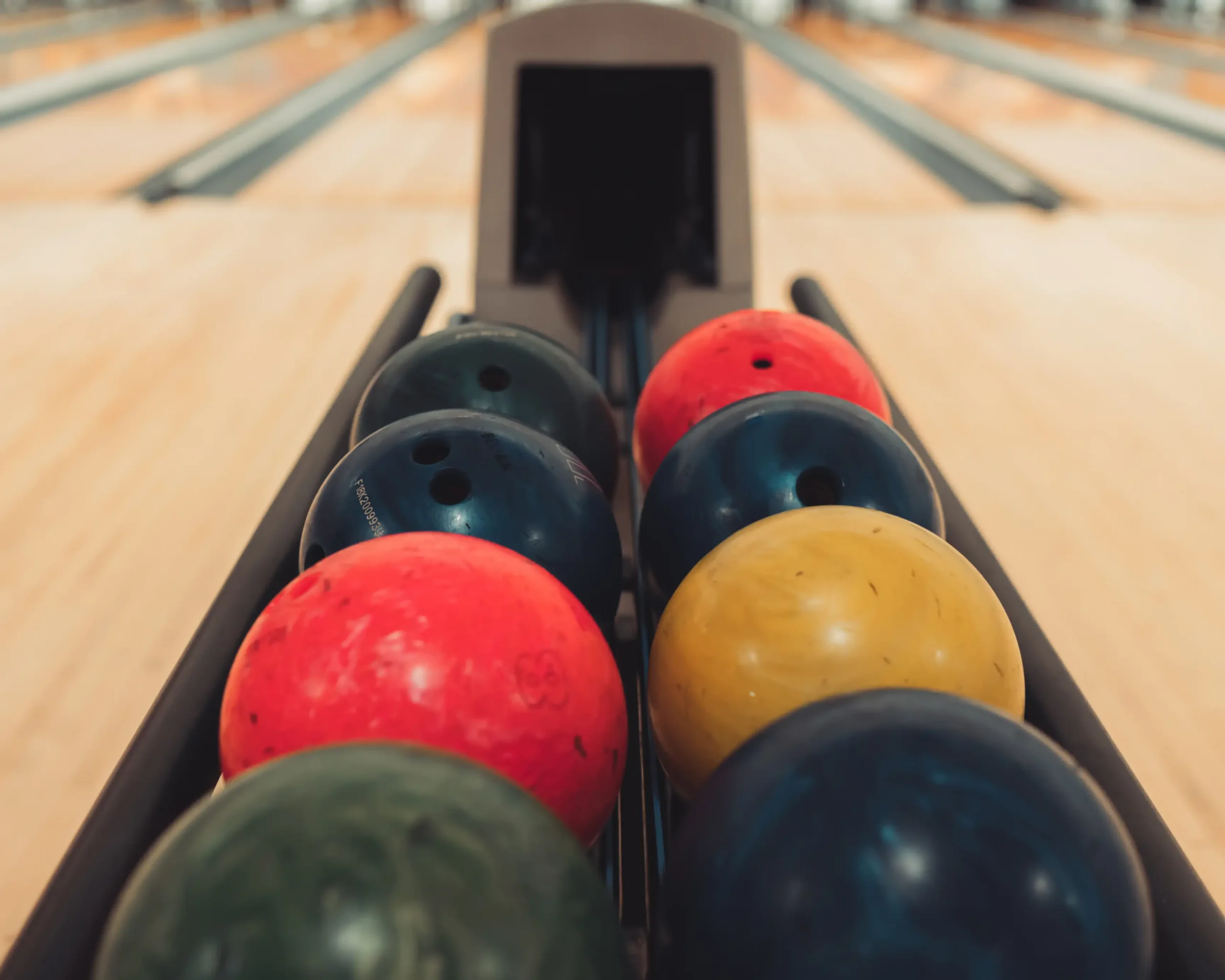 Row of red, yellow, blue, and green bowling balls on the ball return at Bel-Air Bowl in Belleville, IL