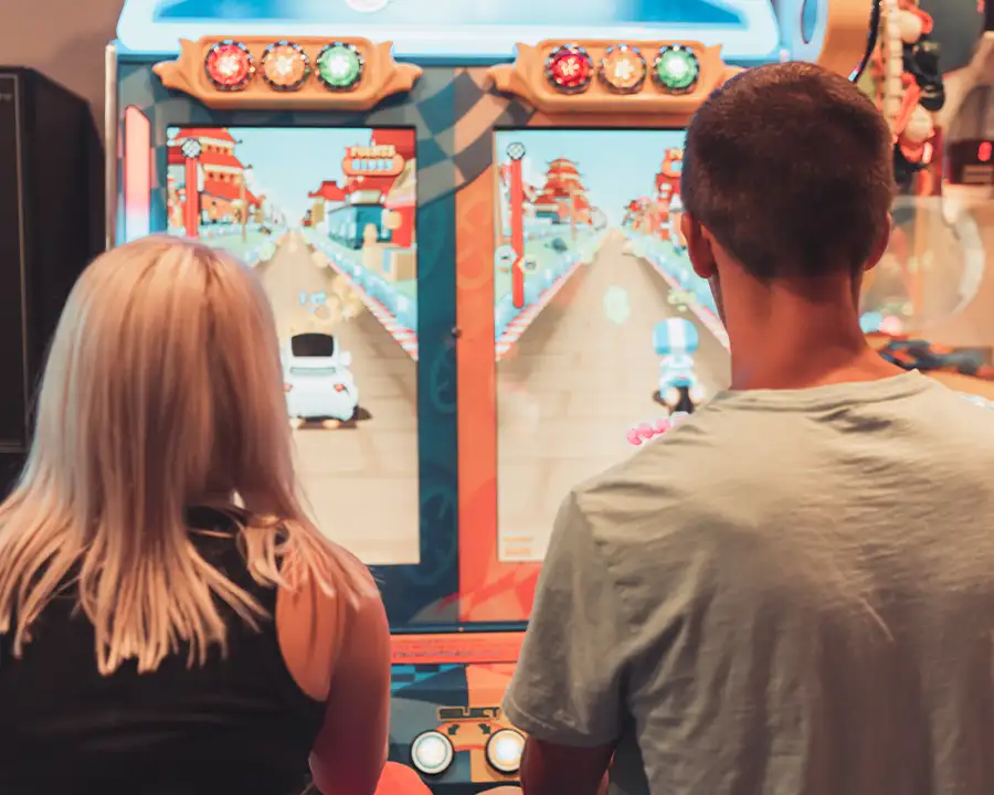 Two players seen from behind at a side-by-side racing arcade game at Bel-Air Bowl in Belleville, IL