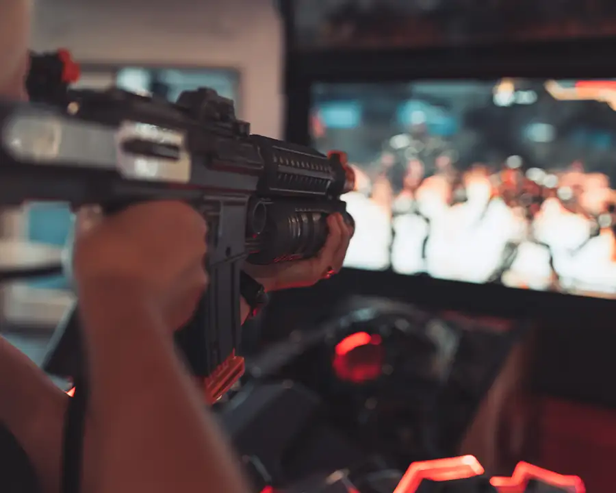 Close-up of a player aiming a gun controller at a shooter arcade game at Bel-Air Bowl in Belleville, IL